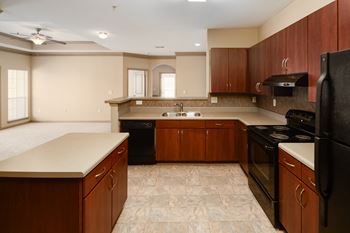 A kitchen with dark wood cabinets and black appliances.